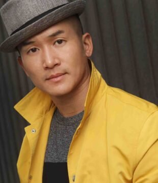 Vinh Headshot Yellow Jacket Stylish DJ Vinom wearing a hat and yellow jacket for a modern, professional DJ appearance.